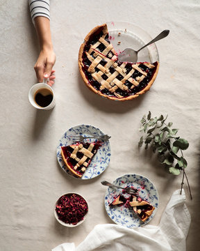 From Above Crop Person Sitting At Covered Table With Served Coffee And Delicious Baked Berry Pie On White Background