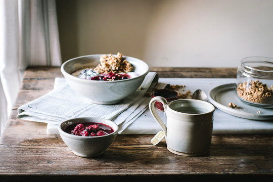 Delicious breakfast bowl with quinoa, rice and groats near tea cup and newspaper
