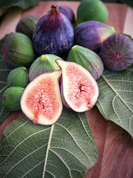 chopped fig and figs over wooden table with green leaves