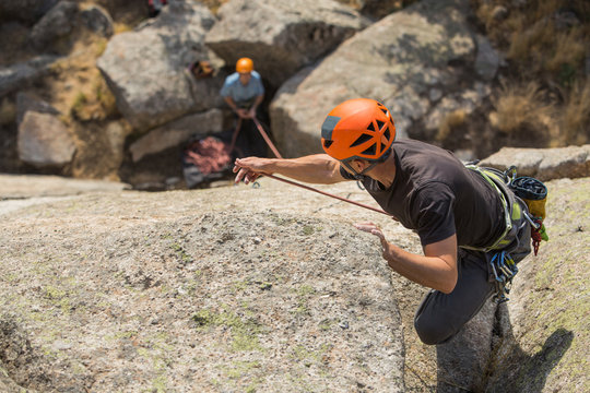 From above young adventurers climbing mountain wearing safety harness against picturesque landscape