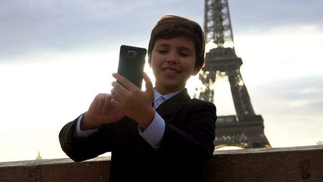 Handsome teenager boy makes selfie on the phone against the backdrop of the Eiffel Tower, Paris, France