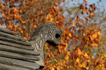 ornately carved wooden dragon head on the roof of a viking house