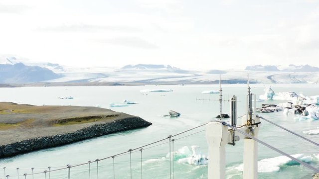 Aerial ascending shot of the jokulsarlon lake in Iceland with a bridge in first term.