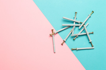 Plastic wall plugs and self-tapping screws on colored background