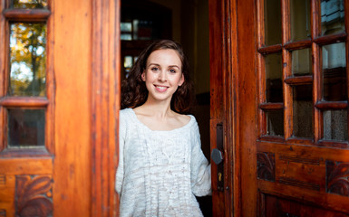 Young beautiful woman standing in old stylish door of building