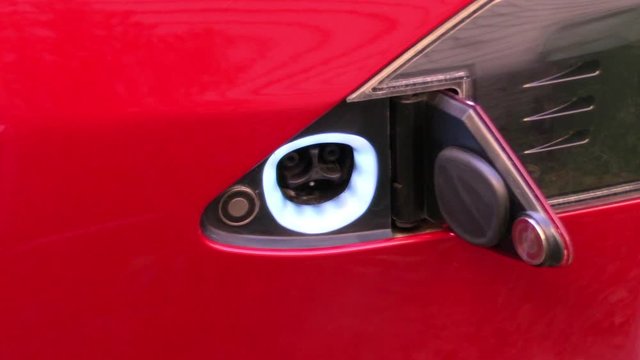 Male Hand Plugging In EV Charge Port At Home For Electric Car