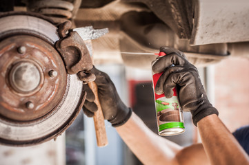 Car master mechanic repairer lubricates screws with machine cleaner spray