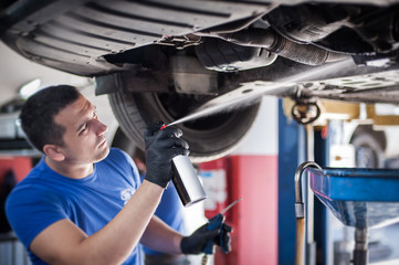 Car master mechanic repairer lubricates screws with machine cleaner spray