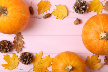 Autumn background with leaves and pumpkins on a colored background top view. Thanksgiving concept.