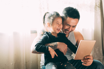 Father wth tattoos playing with daughter at home
