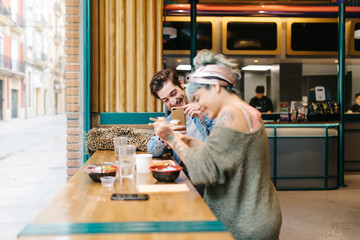 Man taking photo of laughing womanÂ in cafe