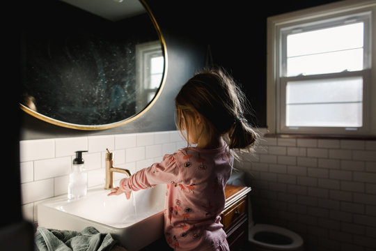 little girl gets ready in bathroom mirror