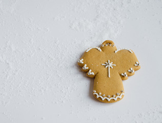 Christmas angel - gingerbread cake lies on a white background. White snow is scattered around.