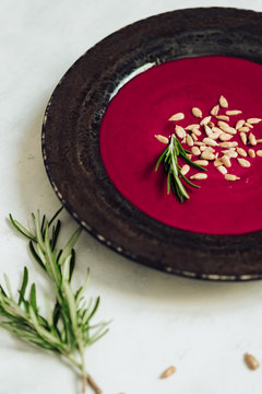 beetroot cream soup with rosemary, grilled sunflower seeds on white table