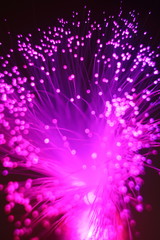 Colored whims of a panicle of a lamp from a bundle of optical fiber threads. An imitation of a salute, explosion or nebula with dots of bright stars, a expanding universe.
