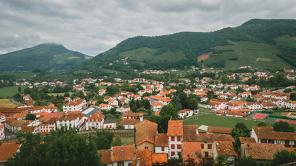 Fototapeta na wymiar Mountain village with orange roofs and mountains in the background in a cloudy day. (panoramic)