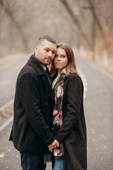 Family story. Lovely couple hug and love outdoor. People dressing in black coat.