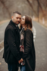 Family story. Lovely couple hug and love outdoor. People dressing in black coat.