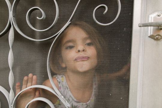 little girl looks out door