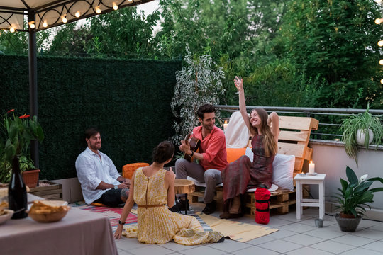 Friends having fun and playing a guitar during a rooftop party
