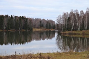 Fototapeta premium Autumn landscape: a forest lake, around which a mixed forest grows.