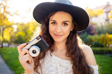Lifestyle portrait of stylish girl with retro camera during walk in city street