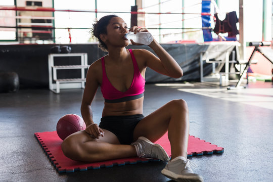 strong black woman drinking water after fitness workout