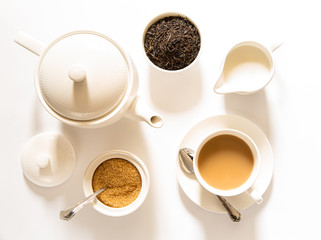 Traditional English breakfast black tea with milk -tea leaves. teacup, teapot, sugar and milk bowls on a white background, top view.