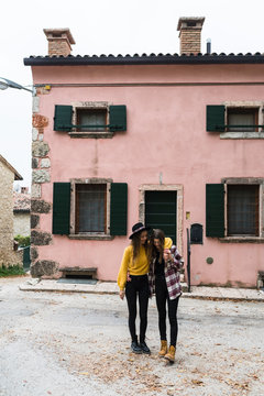 Two girl friends in front of a rustic house