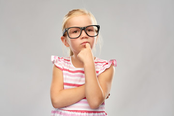 education, school and vision concept - cute little girl in black glasses over grey background