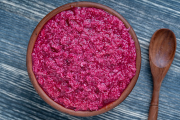 Obraz na płótnie Canvas Red horseradish sauce with beetroot isolated on wooden background, closeup, top view. Concept of healthy eating