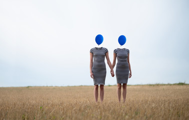 Two Women heads replaced by blue balloons