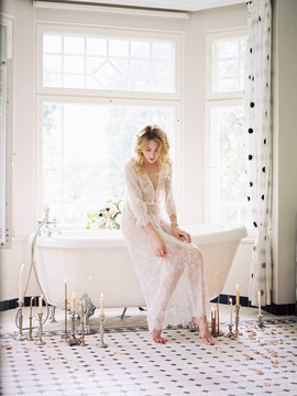 Woman in lace peignoir sitting on bath