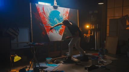 Talented Artist Working on Abstract Painting, Uses Paint Brush To Create Daringly Emotional Modern Picture. Dark Creative Studio Large Canvas Stands on Easel Illuminated.