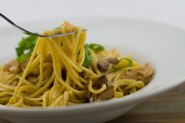 Creamy spaghetti with chicken and mixed mushrooms. Sprinkled with spring onions cut into rings. Freshly prepared and served as a healthy and fast meal of Italian cuisine.