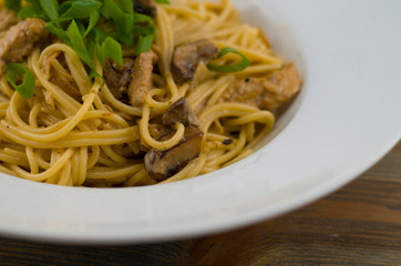 Creamy spaghetti with chicken and mixed mushrooms. Sprinkled with spring onions cut into rings. Freshly prepared and served as a healthy and fast meal of Italian cuisine.