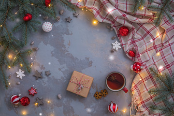 Christmas tea cup with cinnamon, cookies, Fir Tree Branches, toys, presents, plaid on concrete linen background