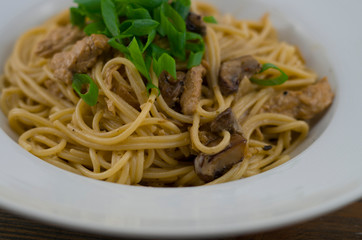 Creamy spaghetti with chicken and mixed mushrooms. Sprinkled with spring onions cut into rings. Freshly prepared and served as a healthy and fast meal of Italian cuisine.