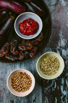 Ingredients of a middle eastern dish, which include aubergine, fennel, dates and harissa paste.