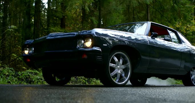 black classical automobile is moving on wet road in forest in daytime, slow motion shot