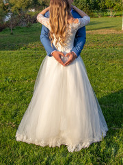 Fototapeta premium Newlyweds hugging. The groom makes heart shape with his hands on the dress of the bride.