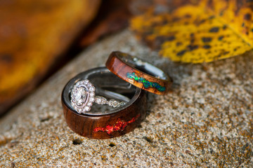 Engagement and wooden fire opal wedding rings in a fall background