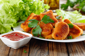 Fried chicken nuggets with ketchup sprinkled with chopped parsley.