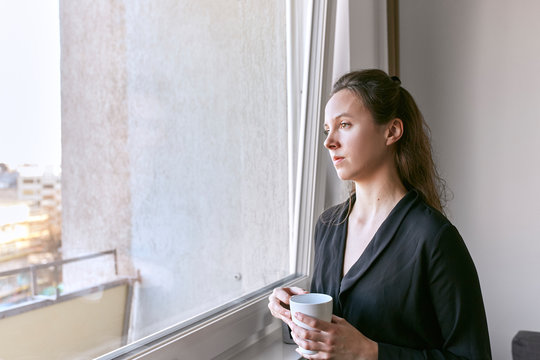 A stylish lady having a drink by the window.
