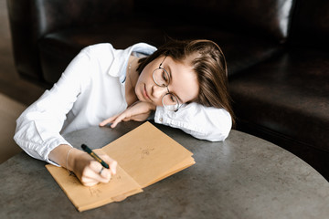 Dreamy girl drawing in notepad