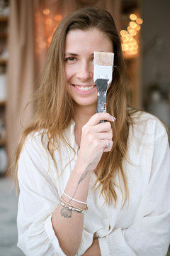 funny portrait of a cute young girl who poses with a brush in paint