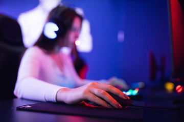 Streamer beautiful girl professional gamer playing online games computer with headphones, red and blue color