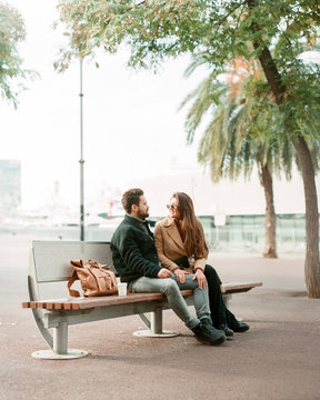 young stylish couple is sitting on a bench and relaxing
