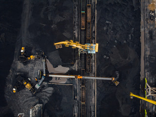Loading coal anthracite mining in port on cargo tanker ship with crane bucket of train. Aerial top...