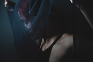 Obraz premium Sad woman in a black veil is standing in a dark studio. Halloween Dead Bride Costume. Profile of a grieving girl.